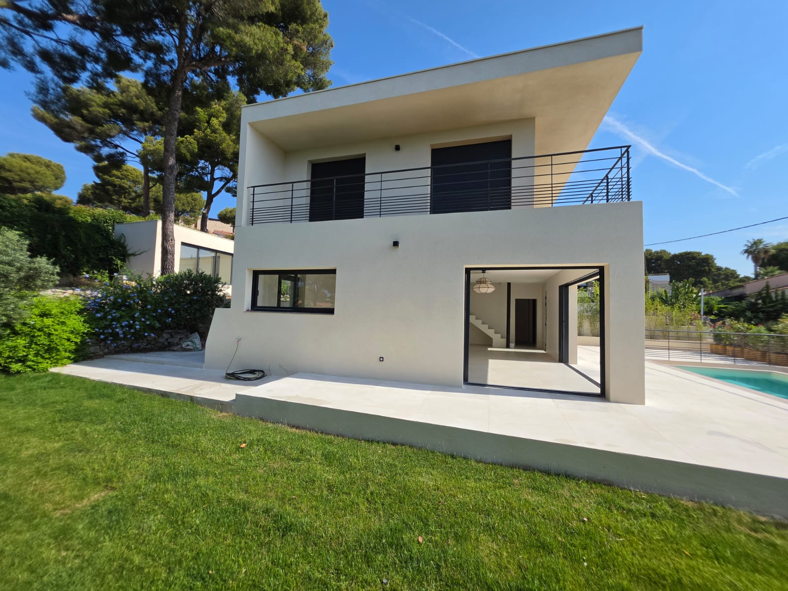 La villa, sa pelouse et sa piscine sous les pins