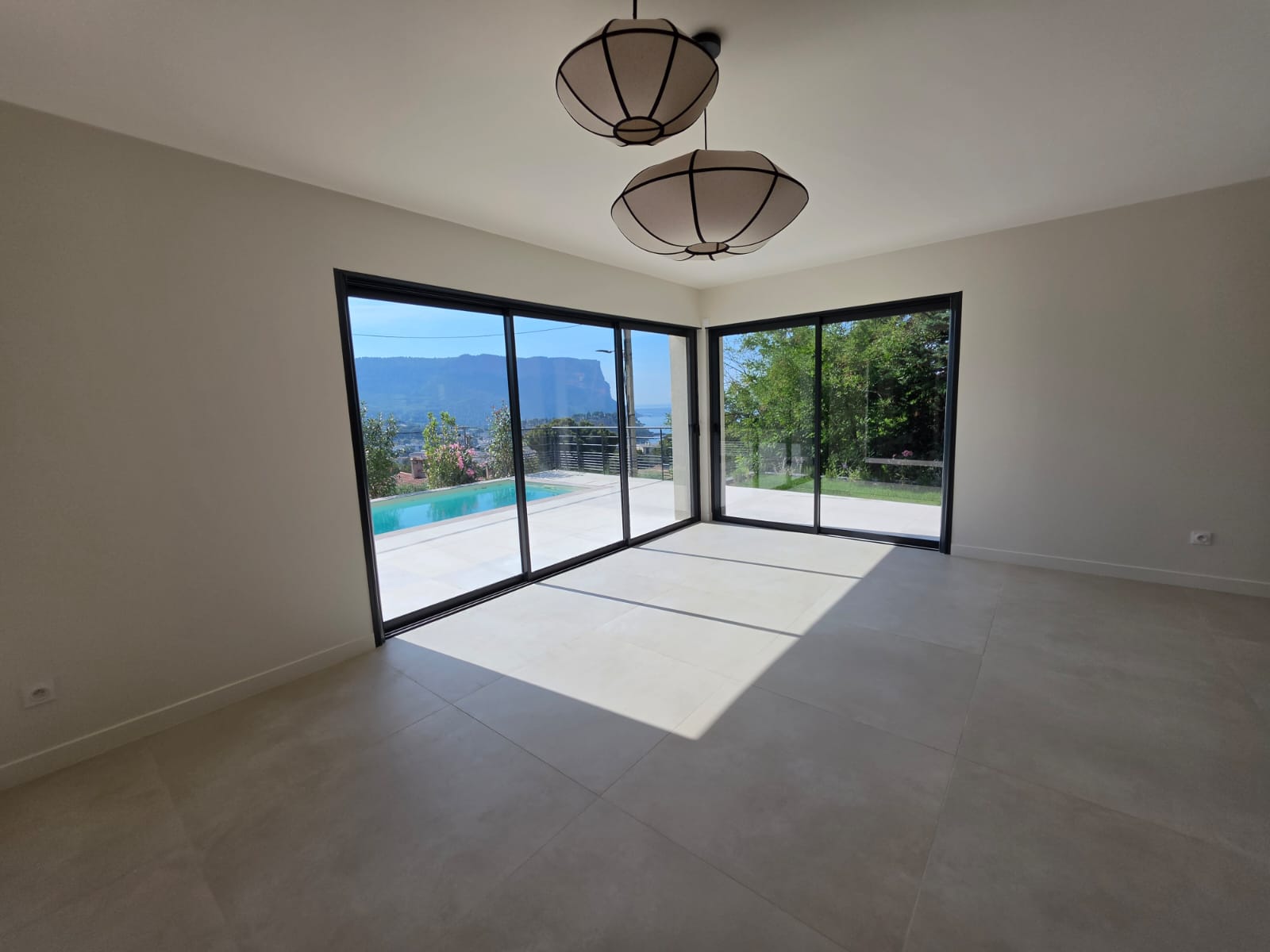 La pièce de vie de 52 m², ses baies d'angle sur la piscine et la mer