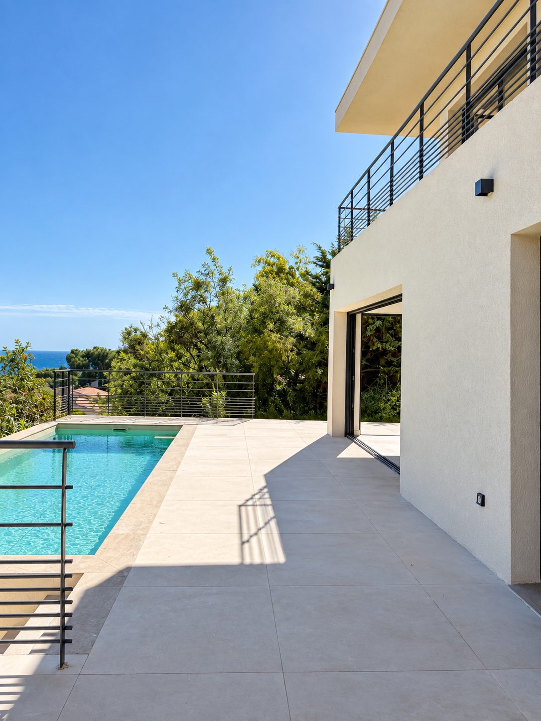 La piscine le long de la terrasse, la mer à l'horizon